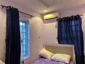 a bedroom with a bed with a blue curtain and a window at Lux Apartment in Agege