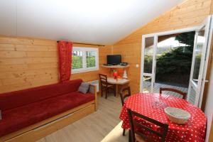een woonkamer met een rode bank en een tafel bij Chalets de la Plaine in Villebret