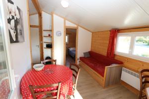 een kleine kamer met een tafel en een rode bank bij Chalets de la Plaine in Villebret