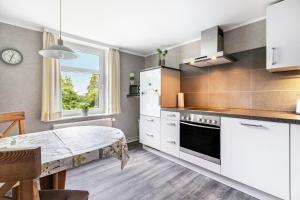 a kitchen with white cabinets and a table and a window at Ferienhof Ibs in Kronprinzenkoog