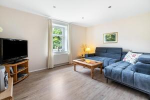 a living room with a blue couch and a tv at Ferienhof Ibs in Kronprinzenkoog