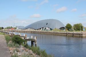 a large domed building next to a body of water at Ferienhof Ibs in Kronprinzenkoog