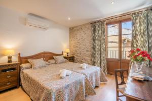 a bedroom with two beds and a table and a window at Ca la Pradina in Pollença