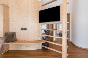 a living room with a tv on a wooden wall at Les Ciases Chalets Dolomites Apt 4 in San Vigilio Di Marebbe