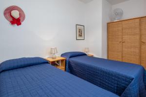 two beds in a bedroom with blue sheets at Holiday house li Piri in San Teodoro
