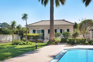 a house with a palm tree and a swimming pool at Olympia Holiday Home in Zakynthos