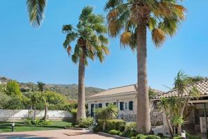 a house with palm trees in front of it at Olympia Holiday Home in Zakynthos