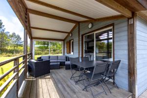a screened porch with a table and chairs on a deck at Chalet parc nature océan in Hourtin