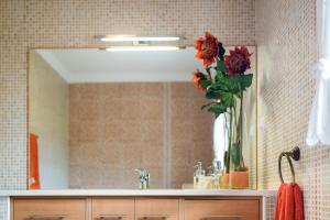 a bathroom mirror with a vase of flowers on a sink at Laguna Formosa in Faro