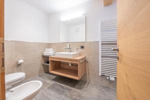 a bathroom with a sink and a toilet and a mirror at App. Erta - Ciasa Lavarella in San Vigilio Di Marebbe +12 photos