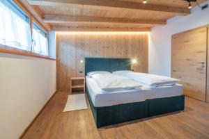 a bedroom with a large bed with a wooden wall at App. Erta - Ciasa Lavarella in San Vigilio Di Marebbe