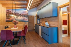 a kitchen with blue cabinets and a table with purple chairs at App. Erta - Ciasa Lavarella in San Vigilio Di Marebbe