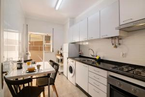 a kitchen with white cabinets and a table and chairs at Âncora B in Monte Gordo