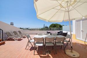 a patio with tables and chairs and an umbrella at Quinta Alegre Tavira T3 in Luz de Tavira
