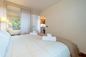 a bedroom with a large white bed with towels on it at Apartamentos Salou - 112 in Salou +14 photos