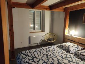 a bedroom with a bed and a chair and a window at Chez nono et vero in Roussillon en Isere