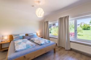 a bedroom with a bed with blue sheets and two windows at Ferienwohnung Linde in Taching am See