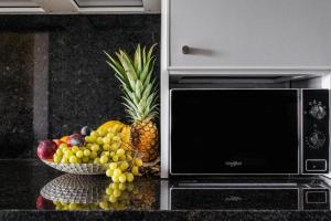 a bowl of fruit on a counter next to a microwave at Sweet Home Madeira in Camacha