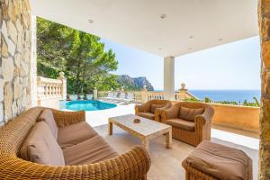 a living room with a couch and chairs and a pool at Villa Cala Llamp in Port d'Andratx