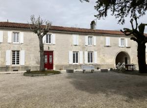a white building with a red door and a tree at Chez Bilhouet in Segonzac