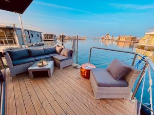 a wooden deck with couches and tables on a boat at Hausboot inkl Motorboot, Ostsee in Heiligenhafen