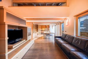 a living room with a leather couch and a flat screen tv at La Pratolina Attico in Castello di Fiemme