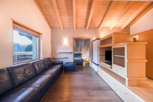 a living room with a leather couch and a tv at La Pratolina Attico in Castello di Fiemme