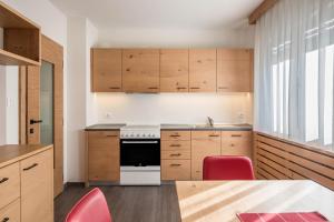 a kitchen with wooden cabinets and a table and red chairs at Ciasa De Marugiana in Gardeccia - San Giovanni di Fassa