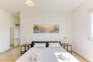 a white bedroom with a bed and two tables at Villa Bianca Appartament in Ugento +62 photos