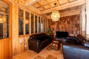 a living room with leather furniture and a television at Villa Bayani Été in Lacanau