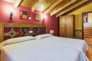 a bedroom with a large white bed with red walls at El Serenal in Santa Maria de Valdeón