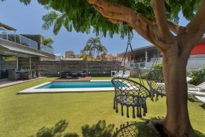 a swing hanging from a tree next to a swimming pool at Villa Playa del Duque in Adeje