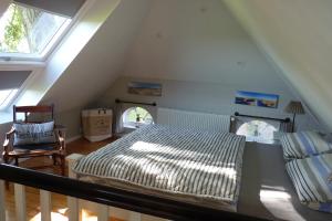 a attic bedroom with a bed and a chair at Feriencottage Nordseeluft in Siekbüll