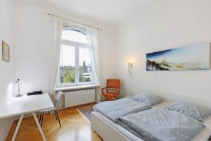 a bedroom with a bed and a desk and a window at Villa am Weinberg in Wiesbaden
