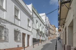a street with white buildings and a person walking down the street at Barsanz Palace Home in Alcalá del Valle