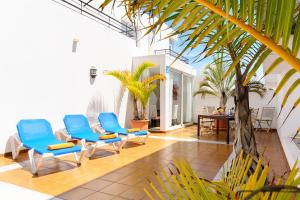 a patio with blue chairs and a table and palm trees at Luis ii in Puerto del Carmen
