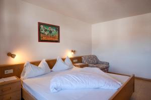 a bedroom with a bed with white sheets and a chair at Apartment 5 - Zur Sonne in Laion
