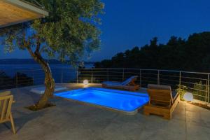 a swimming pool on a patio with a tree at Menagia Village in Agios Georgios