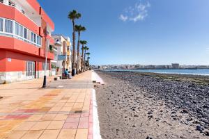 a beach with palm trees and a building at Costamar Arinaga in Arinaga