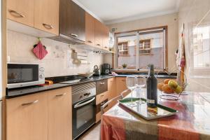 a kitchen with wooden cabinets and a counter with a bottle of wine at Costamar Arinaga in Arinaga