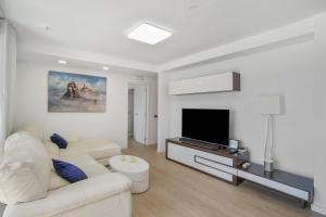 a white living room with a white couch and a tv at Alexandria's Retreat in San Bartolomé