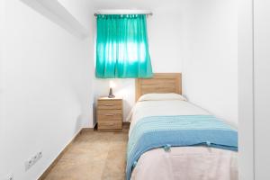 a bedroom with a bed and a blue curtain at Casa Pepe junto al mar in Benajarafe
