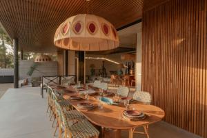 a long wooden table with chairs and a large light fixture at M Villa Comporta Retreat in Carvalhal