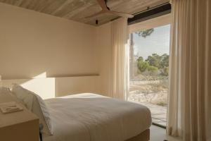 a bedroom with a bed and a large window at M Villa Comporta Retreat in Carvalhal
