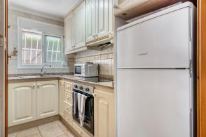 a kitchen with white cabinets and a white refrigerator at La Finca Moraira in Teulada