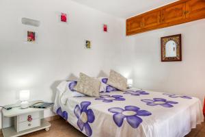 a bedroom with a bed with purple flowers on it at La Finca Moraira in Teulada +12 photos