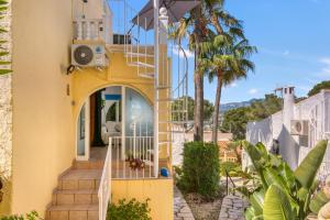 a yellow house with stairs leading up to the front door at La Finca Moraira in Teulada