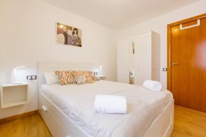 a white bed with two towels on it in a room at Sauc Beach Apartment in Canet de Mar