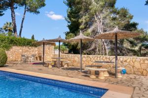 a pool with umbrellas and tables and chairs next to a wall at La Finca Moraira in Teulada