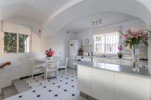 a white kitchen with a table and a vase of flowers at Villa Nerja in Nerja